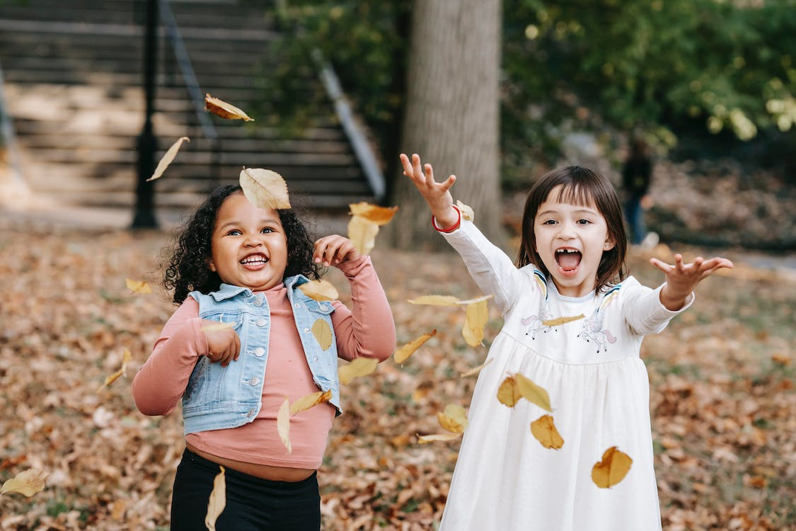 Two Happy kids throwing foliage in the park
