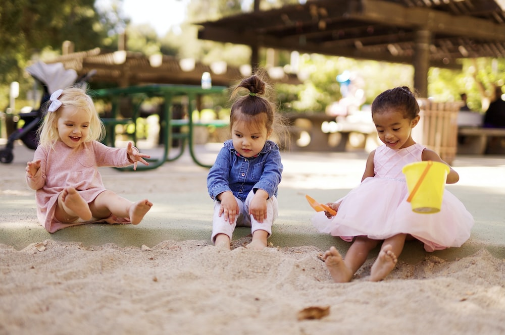 Three little girls playing in the sand Image caption: Little girls having fun in an outdoor playground of a childcare center