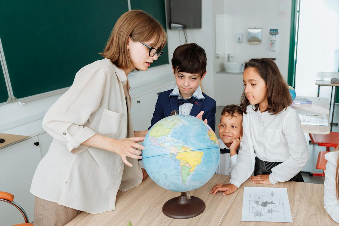 Three children and an adult observing a globe, illustrating early childhood literacy